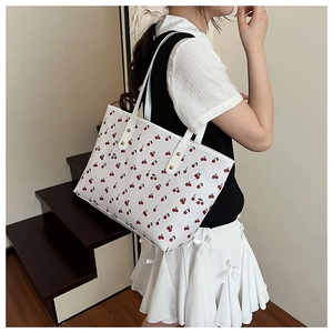 Close-up of fresh white tote bag with red cherry print and golden rivet details