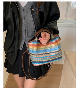 Détail du sac seau en paille à rayures colorées avec poignées et bandoulière en cuir brun