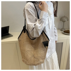 Detail of a large woven straw tote bag with black leather straps and a triangle coin purse