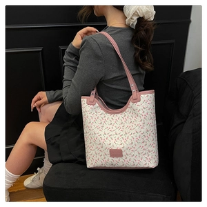 Detail shot of a white floral tote bag with pink straps worn by a model in a dark setting