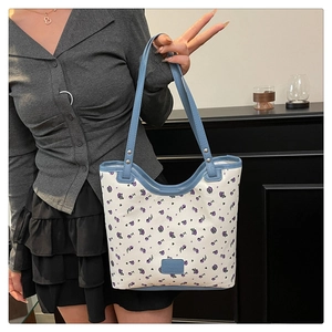 Detail of floral tote bag featuring purple patterns and a blue leather logo patch