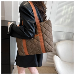 Detail of dark brown quilted tote bag with vibrant orange nylon shoulder straps