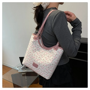 Detailed view of pink floral tote bag with leather straps on a female model