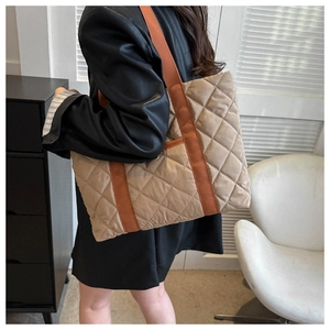 Detailed side view of the khaki quilted tote bag with contrasting orange straps on model