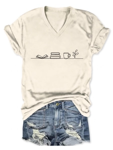 Flat lay of a beige V-neck t-shirt with book and coffee print and denim shorts