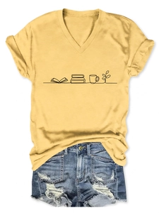 Flat lay of yellow V-neck T-shirt with book and coffee print and ripped denim shorts