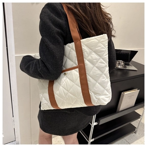 Détail du sac fourre-tout matelassé blanc avec anses brunes et poche à clous dorés