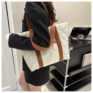 Gros plan sur un sac cabas blanc matelassé avec motif à losanges et anses marron