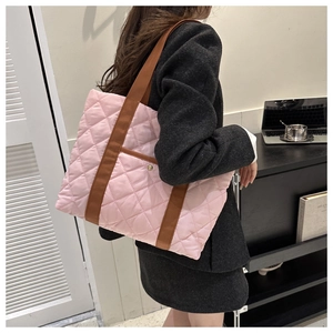 Pink quilted tote bag with brown straps shown in a minimalist modern office setting