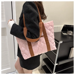 Close-up of pink quilted tote bag with brown strap showing large capacity on model