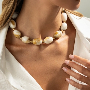 Detail of amber and cream resin beaded necklace with gold spacers on female model