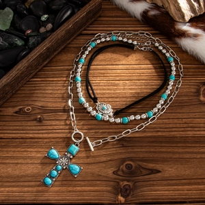 Bohemian multilayer necklace with turquoise cross pendant and flower discs on wood background