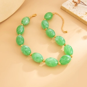 Close-up of green resin beads necklace with gold spacers and lobster clasp detail
