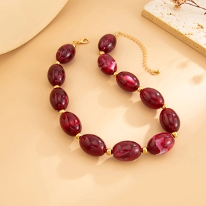 Macro detail of marble-textured resin beads with gold spacers and lobster clasp