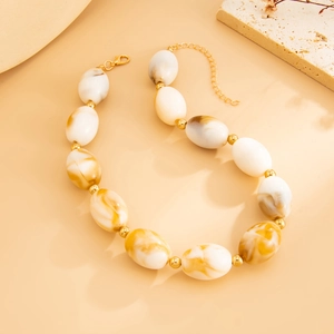 Detail of resin beads with marble texture and golden spacers on a Maillard style necklace
