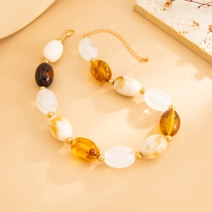 Close-up of amber and marbled resin oval beads on a vintage necklace with gold spacers