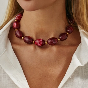 Ethnic style necklace with red resin marble beads and gold spacers on a female model