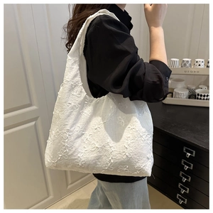 Detailed view of a white lace floral canvas tote bag worn as a shoulder bag on a model