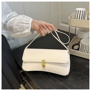 Close-up of a cream baguette bag with a gold metal twist lock and smooth faux leather