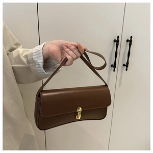 Detail of a vintage dark brown leather baguette bag with a gold buckle and texture