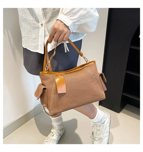 Detailansicht der braunen Canvas-Tasche mit seitlichen Klappentaschen und Kunstledergriffen