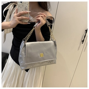 Detail of silver metallic shoulder bag with faux snakeskin texture and gold buckle