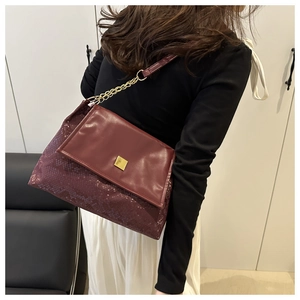 Detailansicht der burgunderroten Ledertasche mit Schlangenmuster und goldener Kette