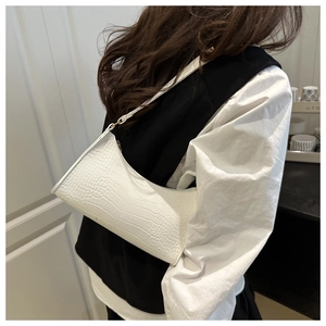 Close-up of white crocodile pattern shoulder bag with golden metal zipper and PU texture
