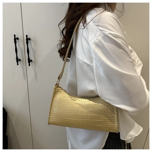 Detail of light yellow baguette bag with crocodile pattern texture and sleek shoulder strap