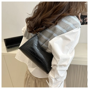 Detail of black crocodile texture shoulder bag with gold metal buckle and strap