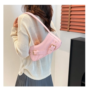 Detail view of pink patent leather saddle bag with gold buckles on a female model