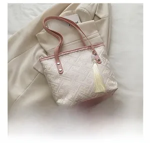 Close-up of pink embroidered pattern and cream tassel on the bucket bag detail