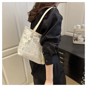 Detail of white jacquard tote bag featuring geometric patterns and elegant side tassels