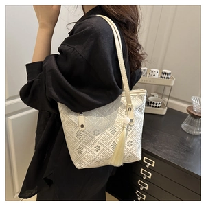 Dettaglio della borsa tote in jacquard beige con trama geometrica e nappa decorativa