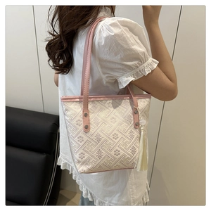Detail of embroidered jacquard tote with traditional geometric patterns and pink tassels