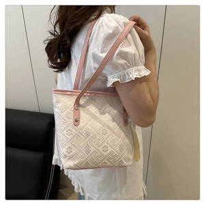 Detail of jacquard tote bag featuring floral patterns, pink leather straps and tassels