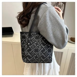 Dettaglio di ricamo floreale jacquard e tracolla in pelle nera su una borsa ampia