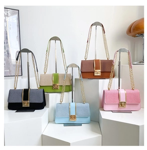 Close-up of five colorful chain flap bags with gold square locks on white pedestals
