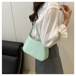 Détail du sac sous le bras en cuir vert menthe avec texte doré FASHION et bandoulière