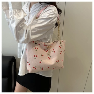 Detail der rosa Canvas-Tasche mit Kirschprint, Kettenriemen und Reh-Anhänger am Modell