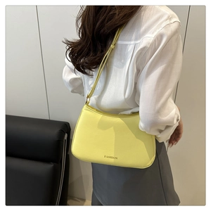 Detailansicht der gelben Schultertasche mit Fashion-Aufdruck am Model in weißem Hemd