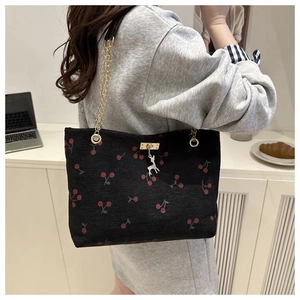 Détail du sac cabas en velours noir avec imprimé cerises et pendentif cerf argenté