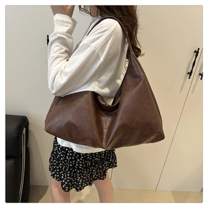 On-shoulder view of large brown hobo tote bag with natural leather texture and minimal style