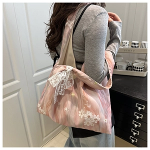Detail of pink floral canvas tote bag featuring 3D white embroidery and a lace bow charm