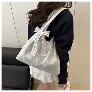Detail of light blue organza tote bag with floral embroidery and large lace bow