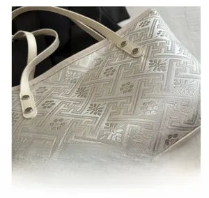 Macro shot of high-quality jacquard fabric texture and silver rivets on a beige tote bag