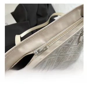 Close-up of smooth silver zipper and embroidered geometric pattern on cream tote bag