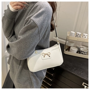Detail view of white lychee pattern leather bag with golden bow and flower zipper pull
