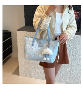 Detail of light blue quilted tote bag with wave embroidery and cute cloud charm pendant