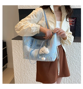Detail of light blue quilted tote bag with colorful wavy patterns and cloud charm
